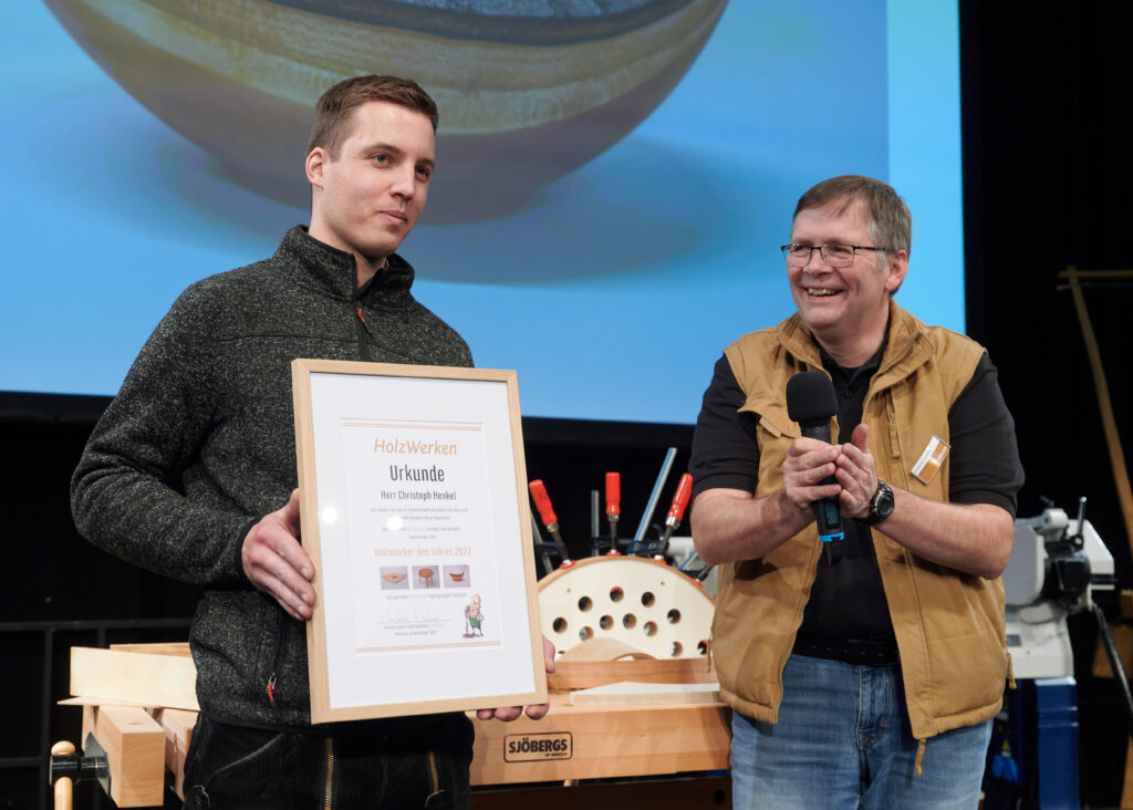 Holzwerker des Jahres 2023 Christopf Henkel mit der Urkunde in der Hand neben Chefredakteur Andreas Duhme auf der Live-Bühne in Fellbach.
