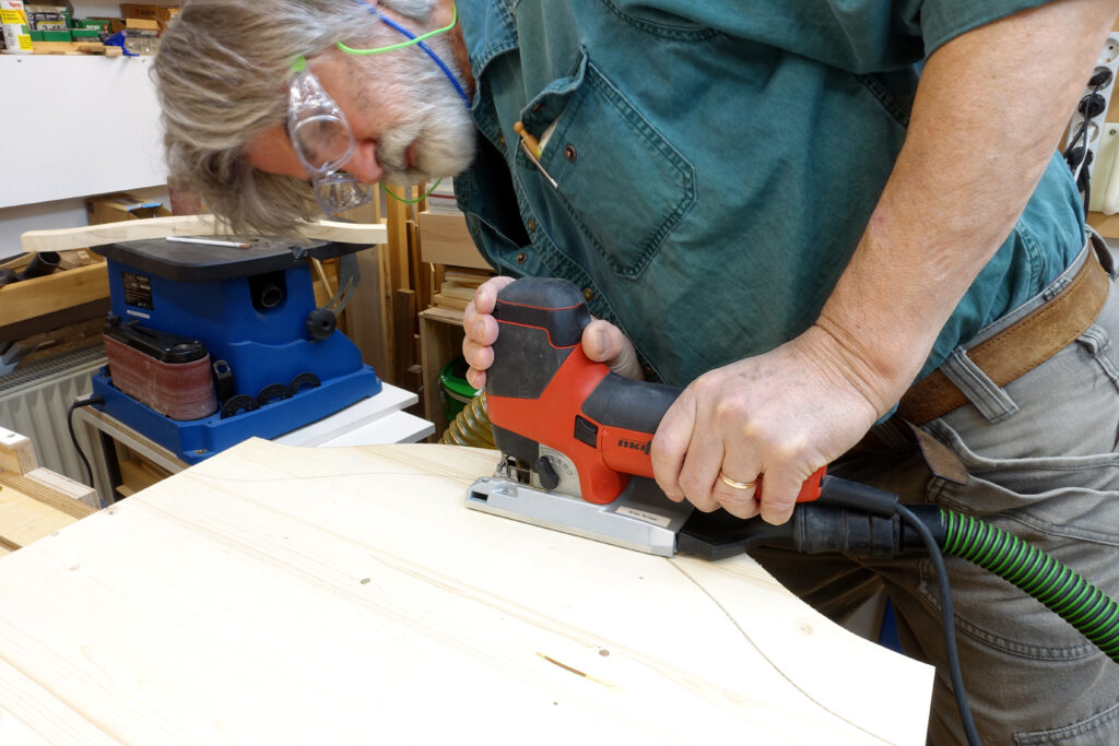 Autor Roland Heilmann bei der Arbeit in seiner Werkstatt mit der Stichsäge an dem von ihm in HolzWerken vorgestellten Beistelltisch.