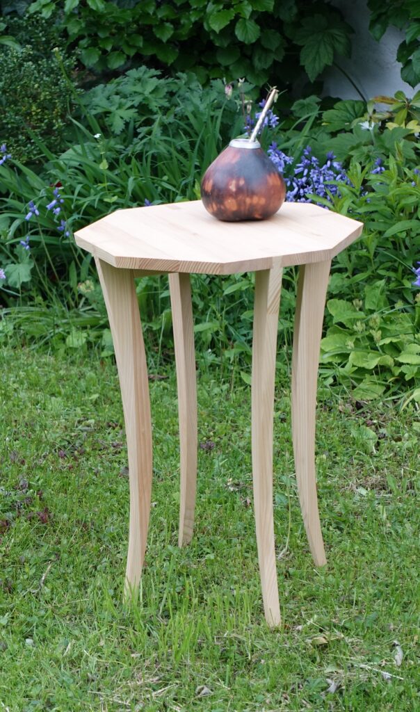 Das im Heft vorgestellte Achtecktischchen steht als fertiges Projekt im Garten mit einem Matetee-Gefäß darauf.