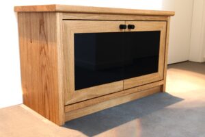 Ein Schuhschrank in Rahmenbauweise steht an der Wand auf einem grauen Teppich.