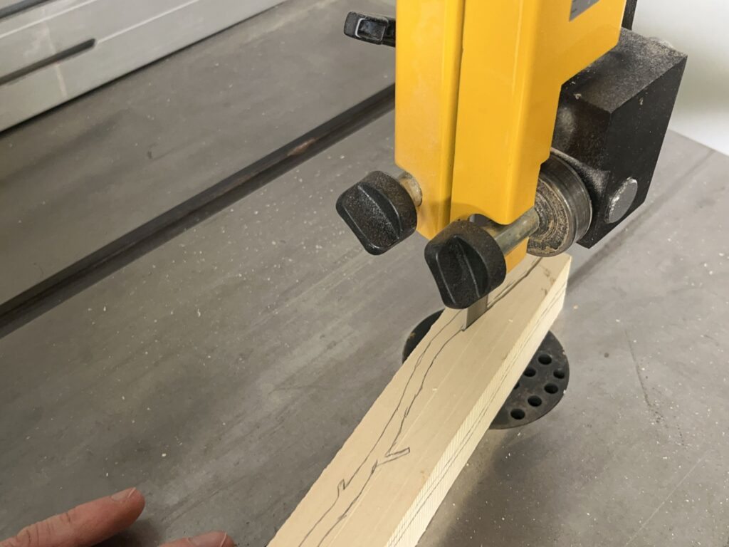 Ein Holzstück wird an der Bandsäge zugeschnitten.