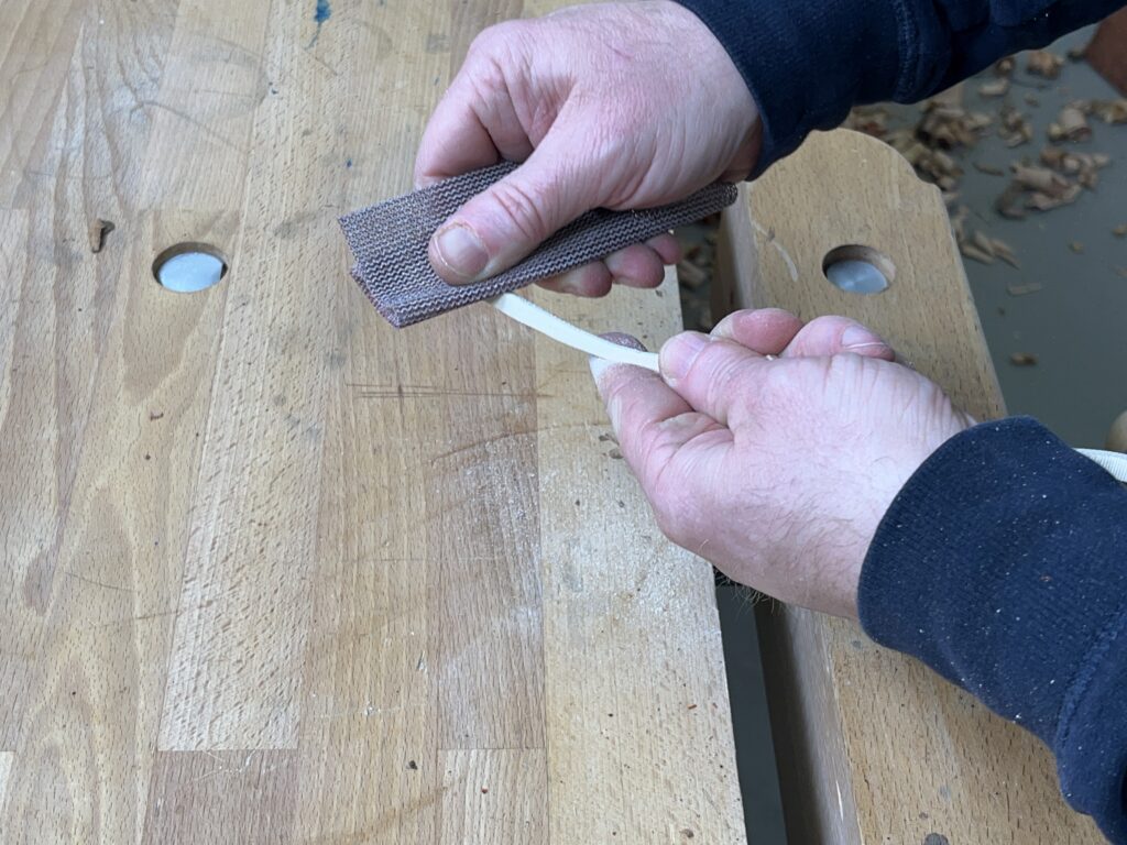 Der Stiel der Holzrose wird abgeschliffen.