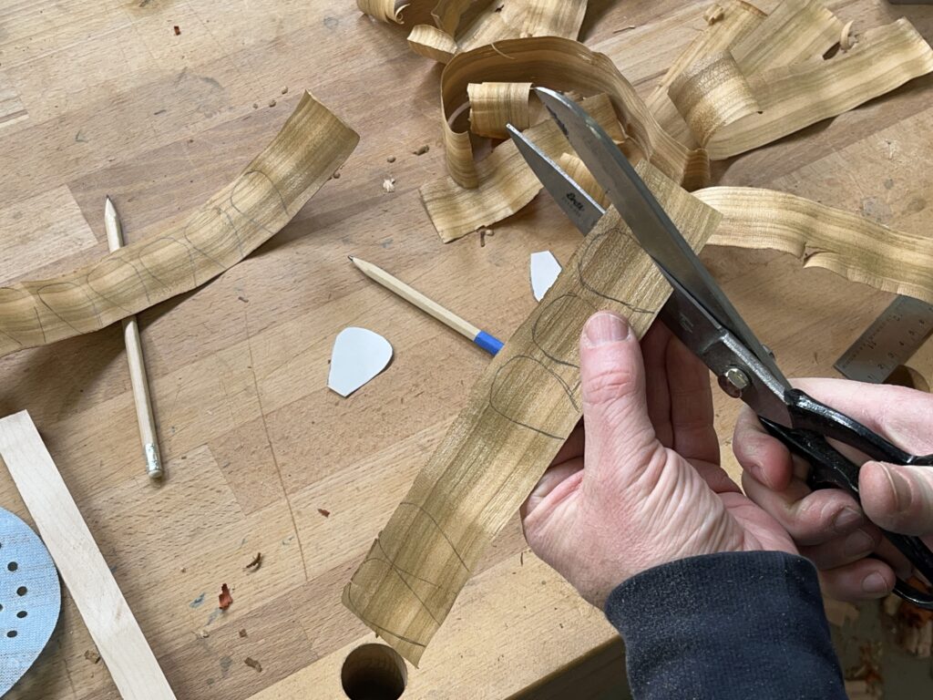 Ein Mann schneidet mit einer Schere Blütenblätter aus einem Hobelspan