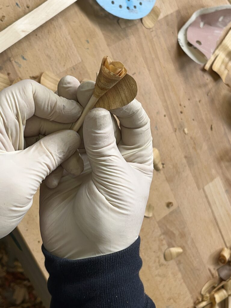 Eine zweite Lage Blütenblätter werden um die Holzrose geklebt.