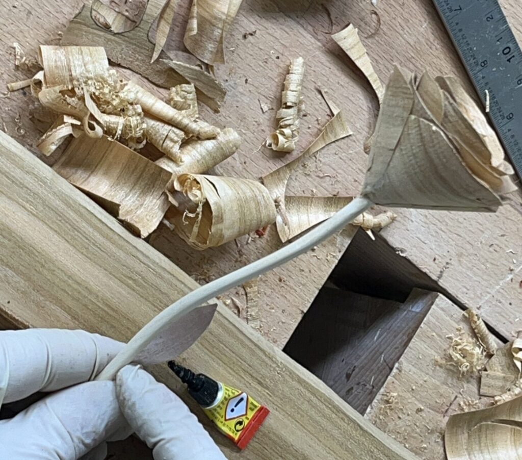 Ein Blatt wird an den Stiel der Holzrose geklebt