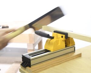 Eine Hand hält eine Japansäge und sägt ein Stück holz ab, das in einen KLemmstock von Stanley eingespannt ist.