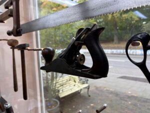 Ein alter Hobel wird in einer Plexiglashalterun im Schaufenster eines Restauraotrs aufbewahrt.