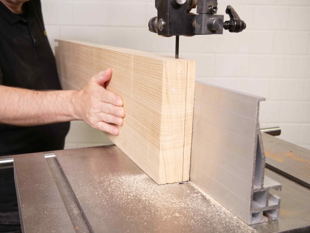 Eine Bohle wird hochkant an der Bandsäge zu dünnen Brettern aufgetrennt.