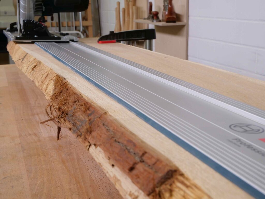 Eine Führungsschiene für eine Handkreissäge liegt auf einer Bohle