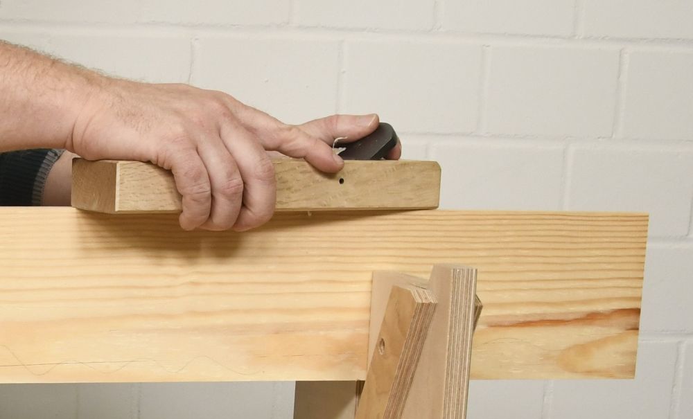 Ein japanischer Hobel wird über ein festgespanntes Holz gezogen.