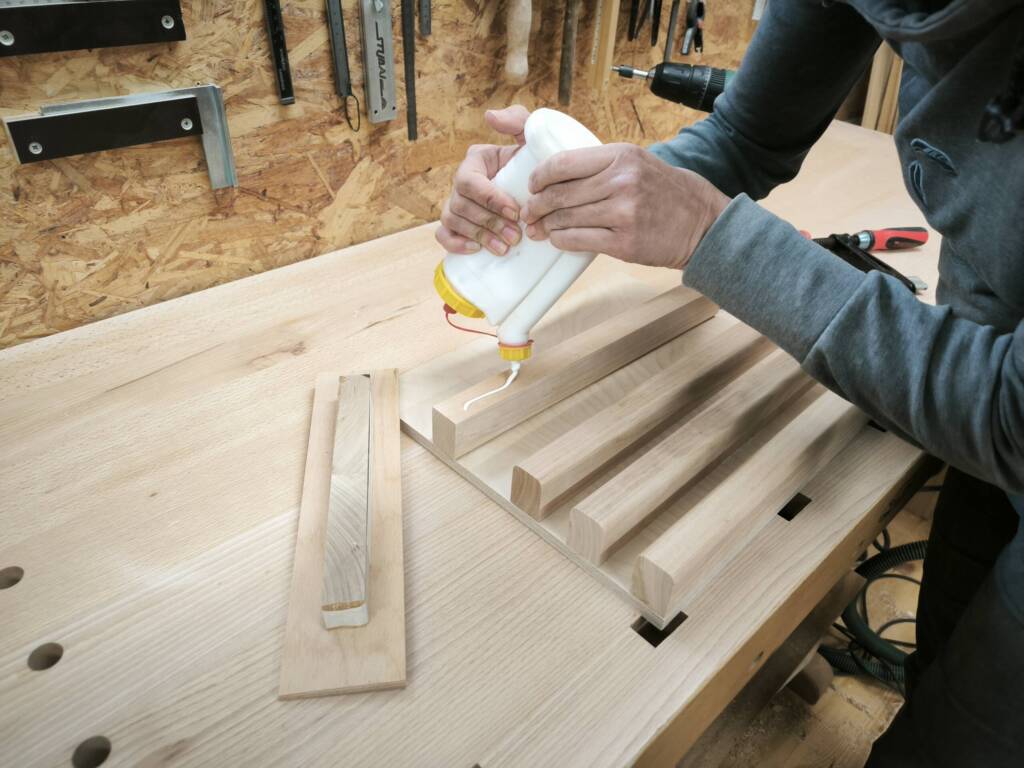 Eine Frau trägt Leim auf ein Werkstück auf.