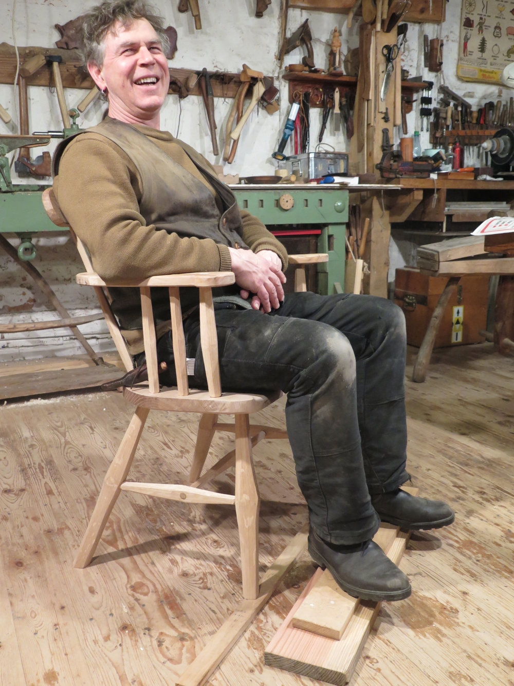 Ein Mann sitzt in einem selbstgebauten Gibson Chair und lächelt in die Kamera.
