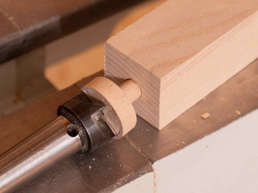 Holzwerkstück mit mittiger Bohrung sitzt stramm auf einem kleinen runden Zapfen, der an einem Drehfutter befestigt ist.