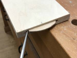 Ein Metallwerkzeug löst eine Holzflachdübelverbindung an einer Sperrholzplatte.