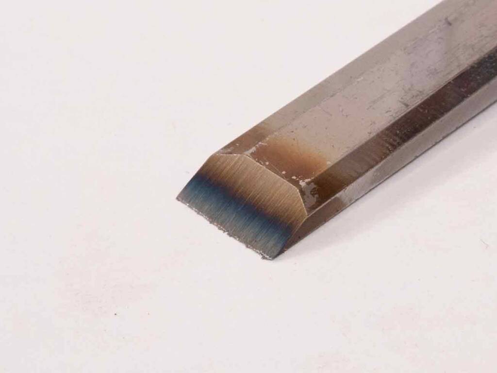 Stechbeitel aus poliertem, blaugehärtetem Stahl mit abgeschrägter Schneide auf hellem Hintergrund.