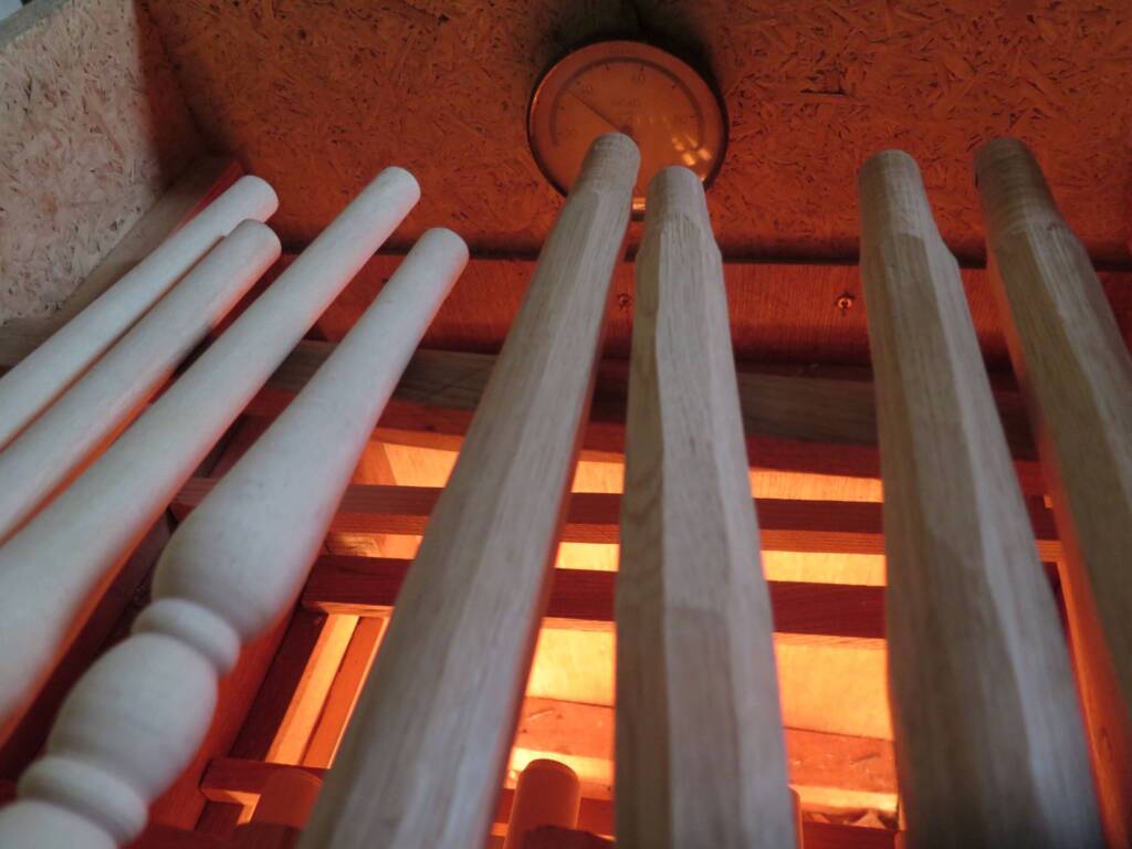 Stuhlbeine liegen in einem beheizten Trockenschrank mit Thermometer.