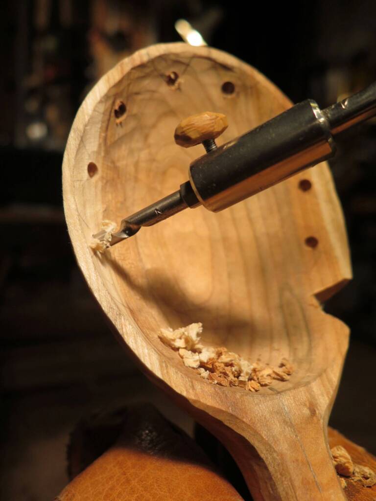 Detailaufnahme eines Löffels beim Aushöhlen mit Werkzeug, Holzspäne im Inneren