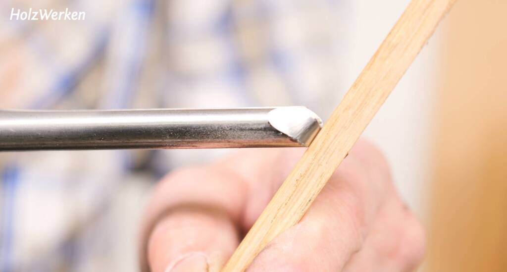 Eine Schalenröhre wird mit der Fase gegen ein dünnes Stück holz gedrückt.