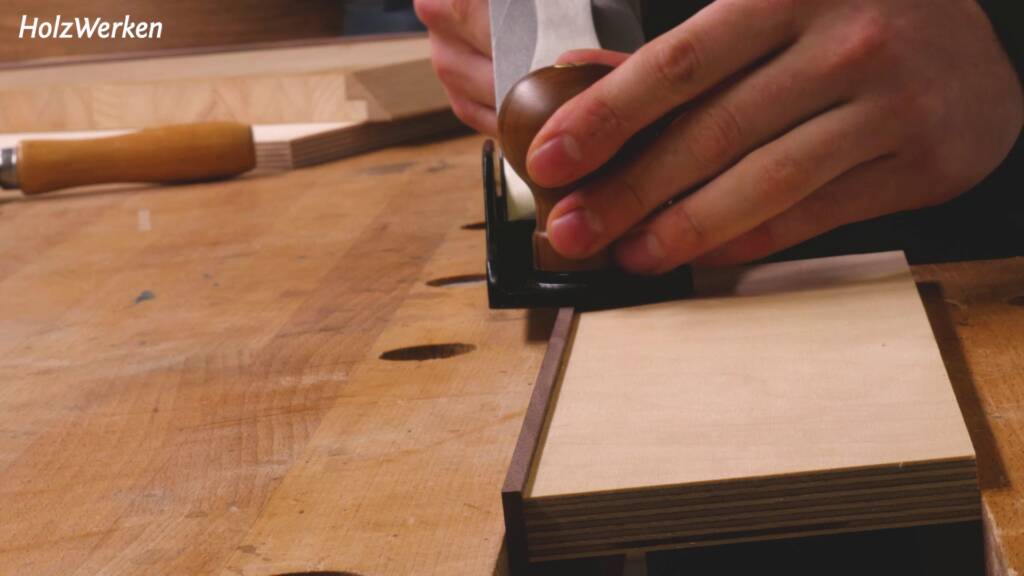 Ein Holzbrett mit einem angeleimten Anleimer wird plan gehobelt.